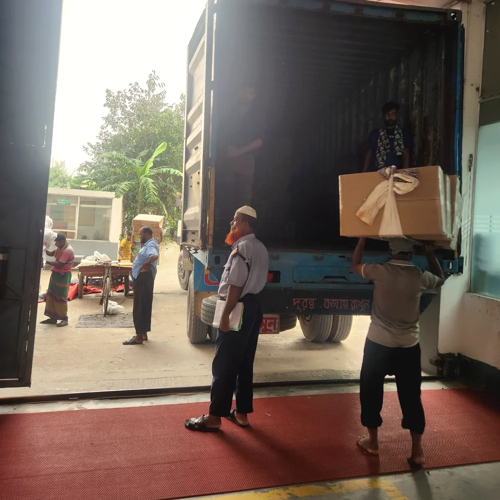 Finished cartons being loaded into a shipping container at a partner factory dock
