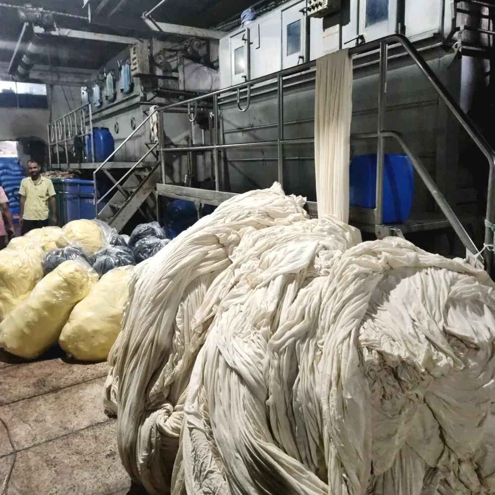 Bundles of greige knit fabric staged on the dye-house floor